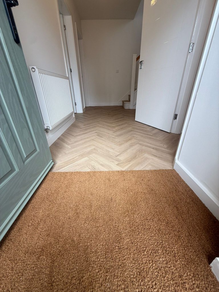 Herringbone LVT flooring with door mat in a new build home by Koti Homes